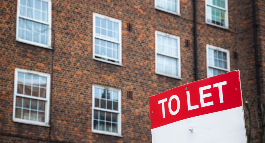 A 'To Let' sign in front of a brown apartment complex