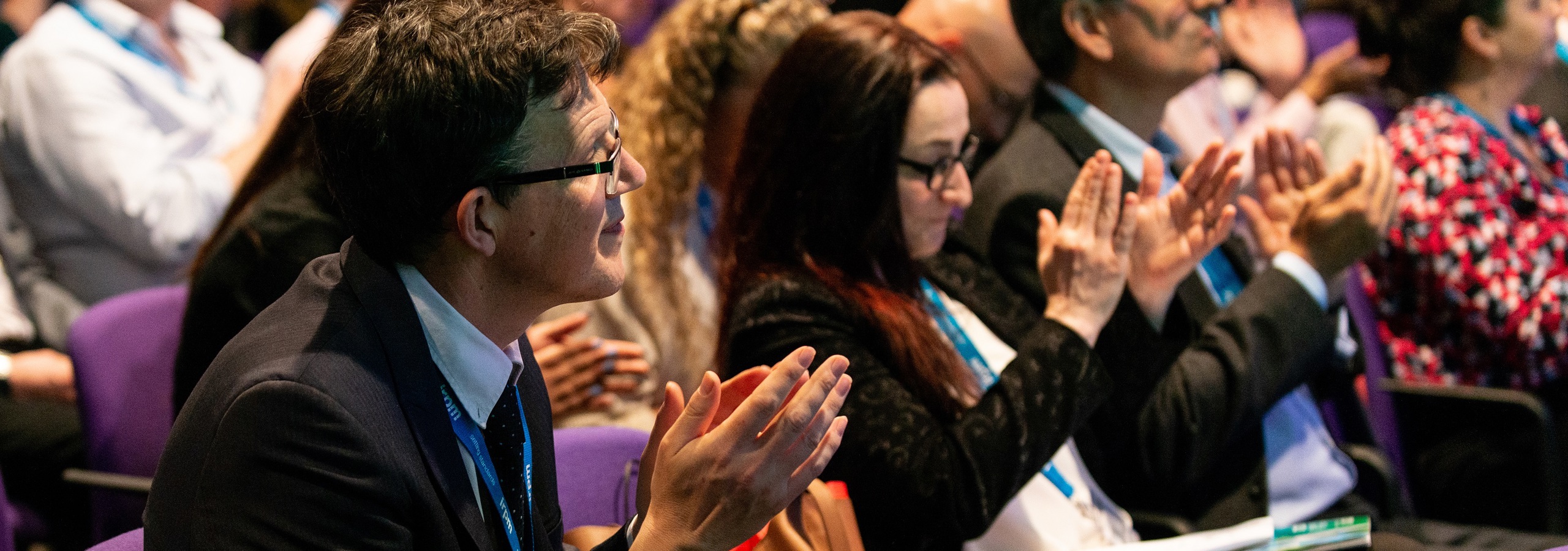 A row of people at a property managers industry event clapping