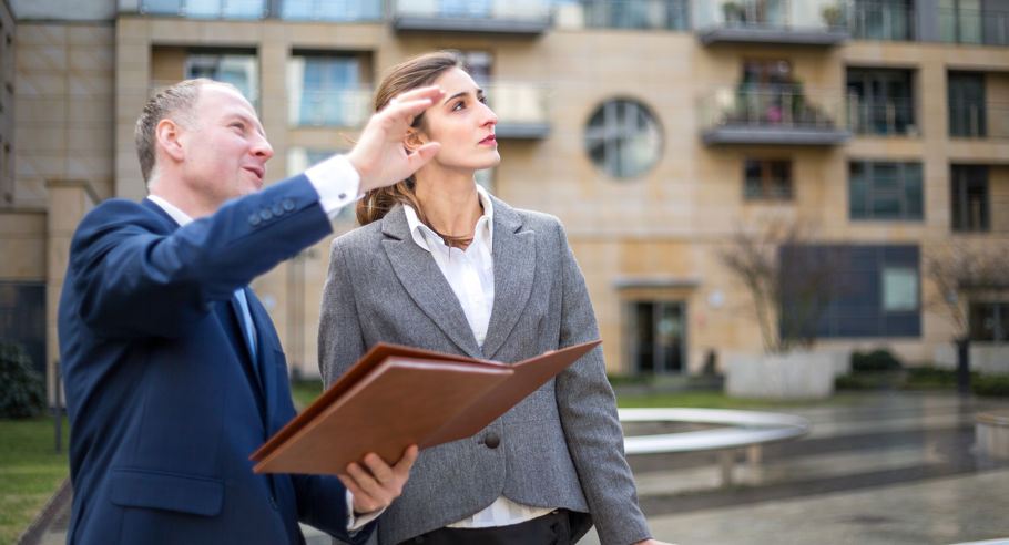 A man holding a clipboard and pointing with a woman 