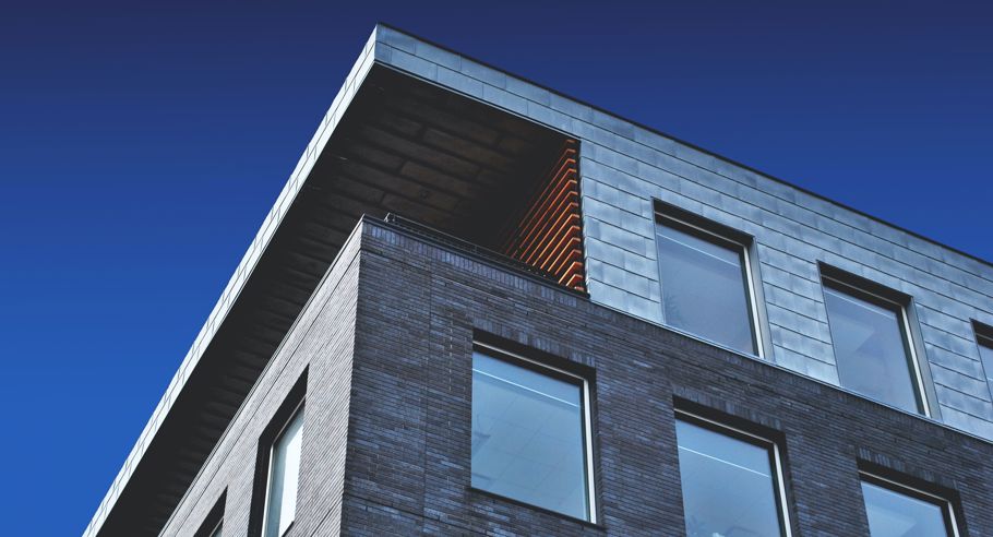 A low angle shot of the corner of an apartment block in front of a blue sky