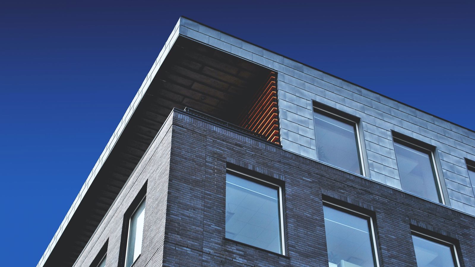 A low angle shot of the corner of an apartment block in front of a blue sky