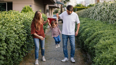 Two parents holding their child in the air on a walkway