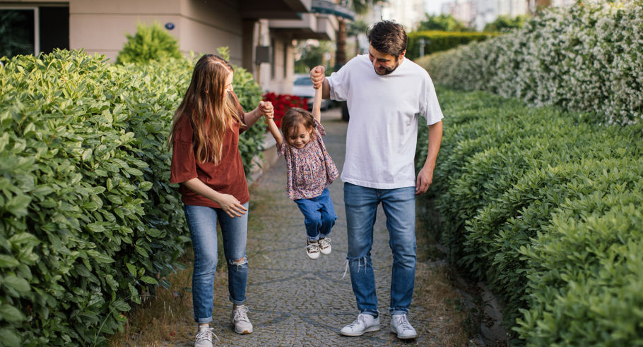 Two parents holding their child in the air on a walkway