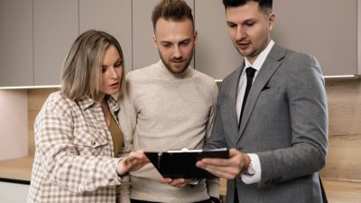 A property manager showing documents on a clipboard to a couple