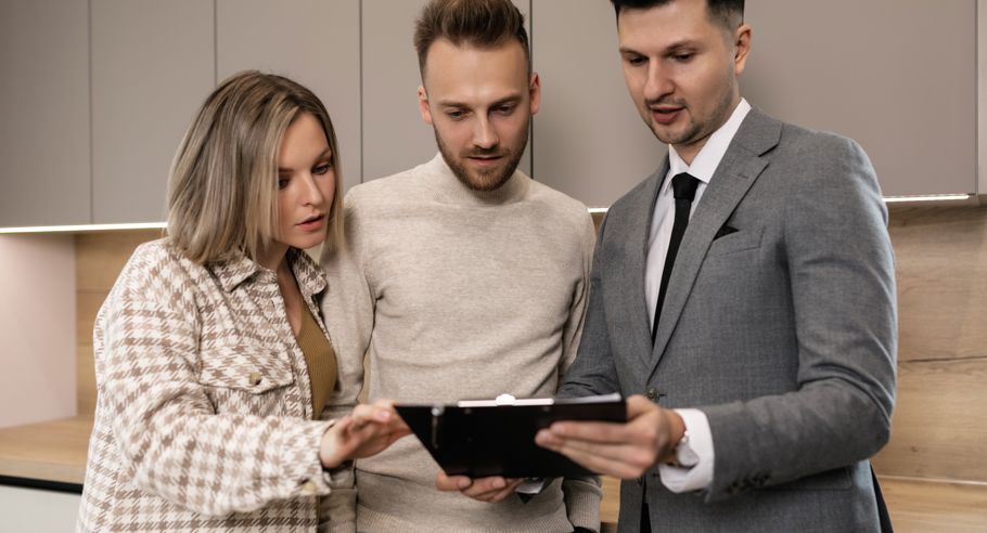 A property manager showing documents on a clipboard to a couple