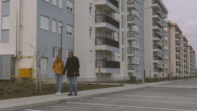 Two people holding hands next to an apartment complex