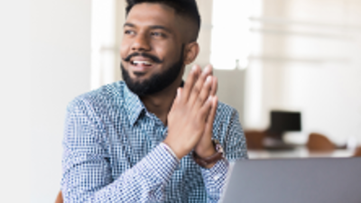 An office worker holding their hands together infront of a laptop