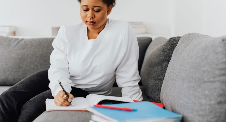 A woman writing in a notepad on a sofa