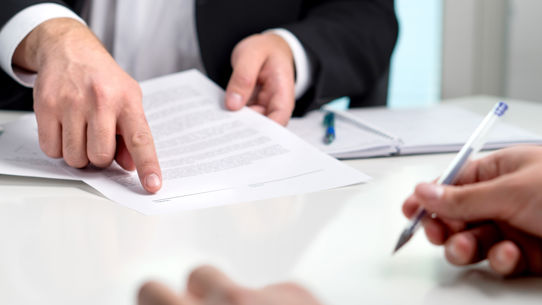 Close up of 2 people signing documents